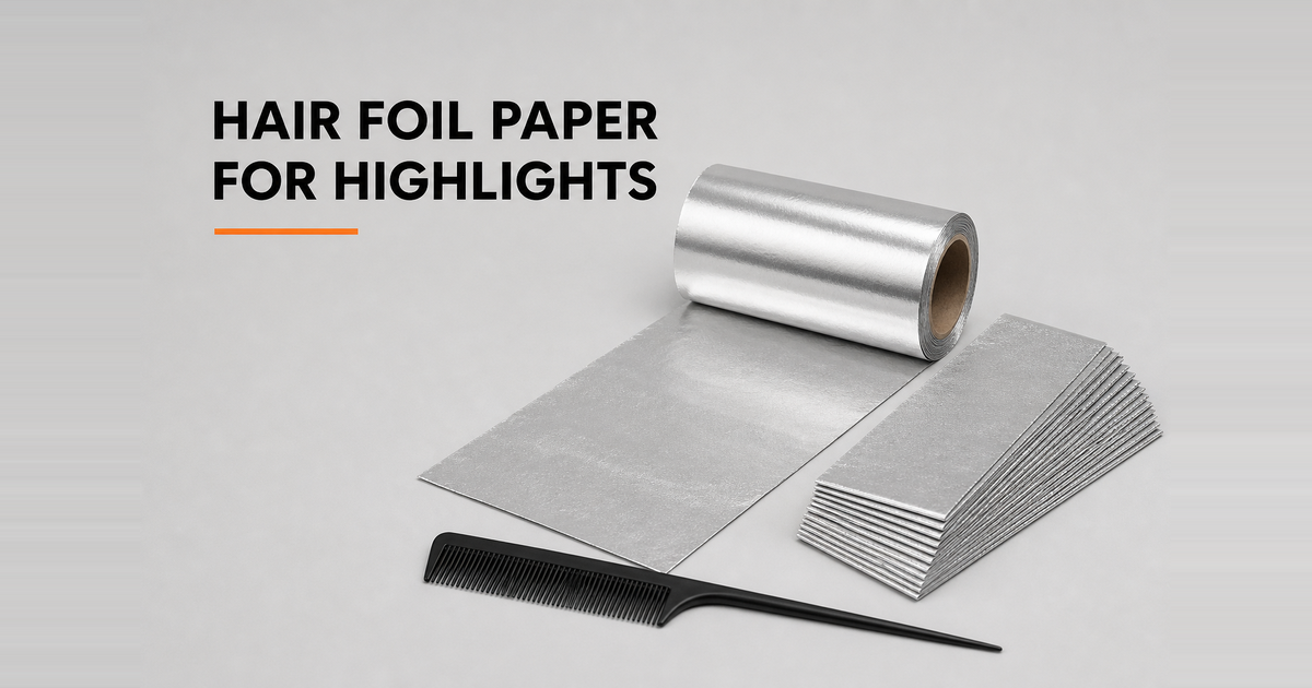 Roll of aluminium hair foil paper with pre-cut foil strips and a tail comb on a grey salon surface